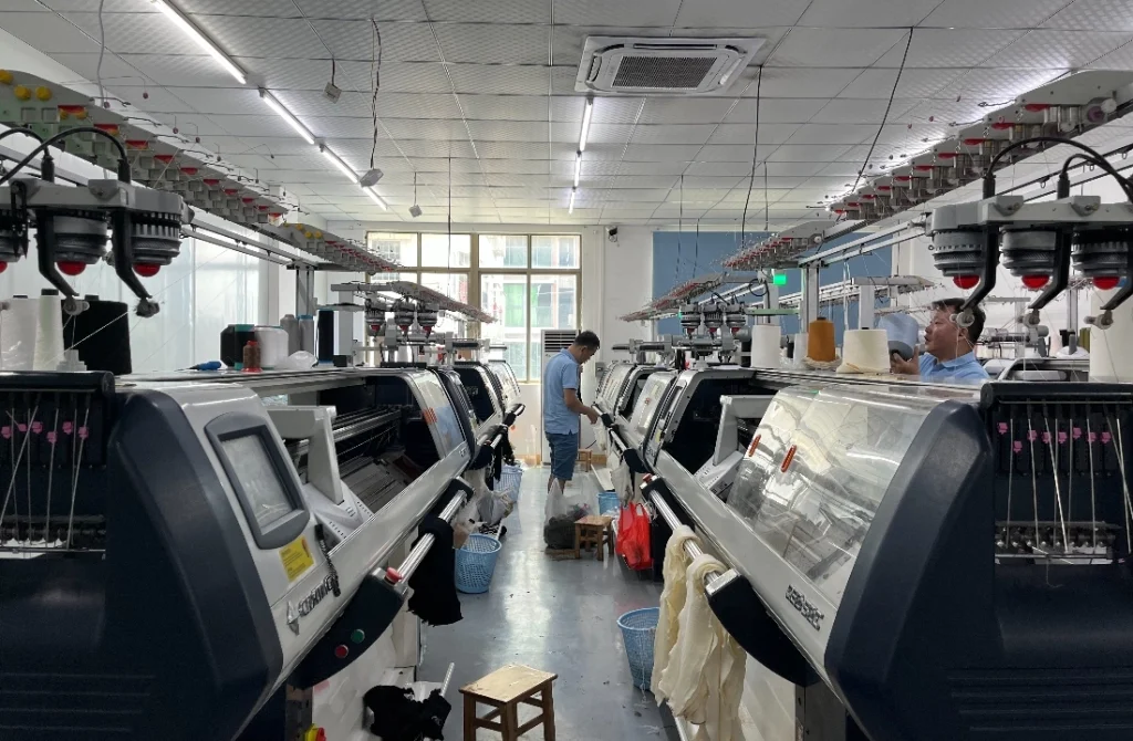 Industrial flat knitting machines used for pullover sweater gauge development in a knitwear factory