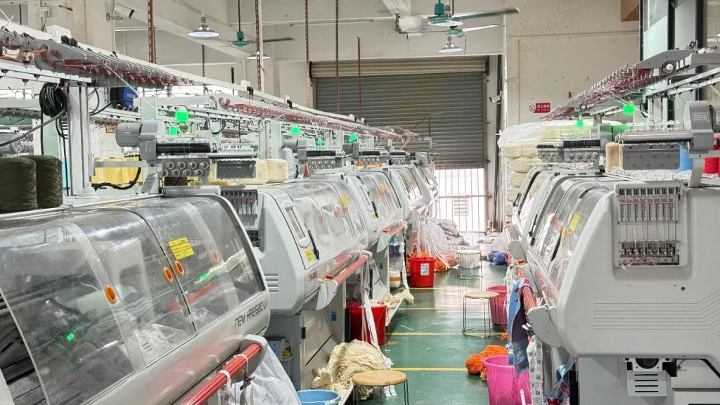 Industrial knitting machines used for cable knit sweater production in a knitwear factory