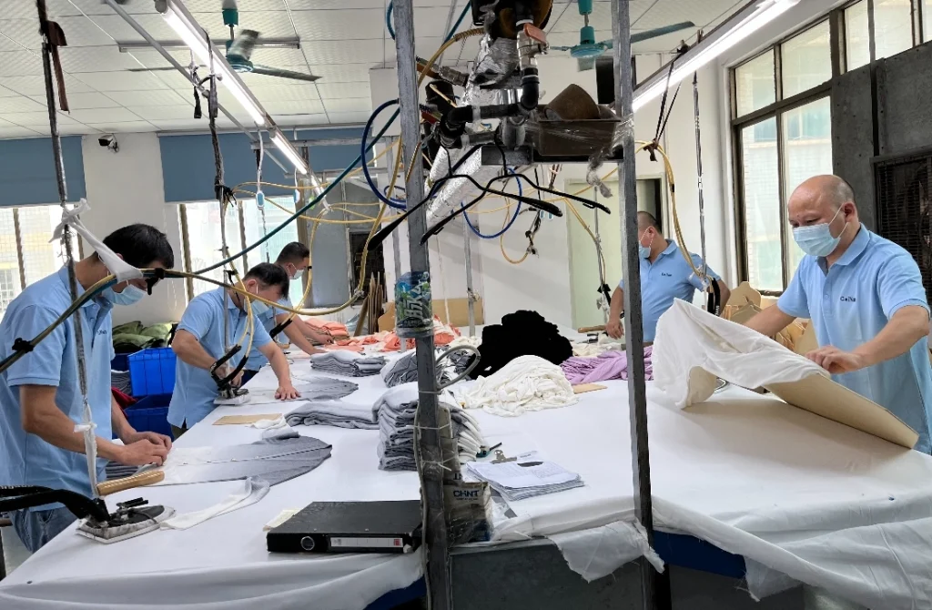 Workers finishing pullover sweater panels during knitwear production and inspection