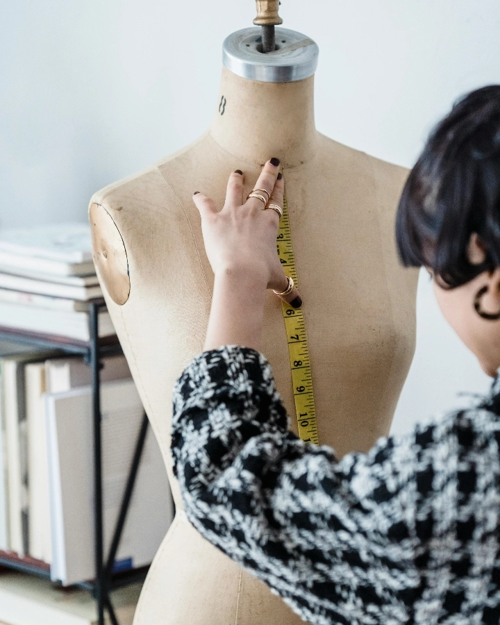 Designer measuring a mannequin for pullover sweater fit and size approval
