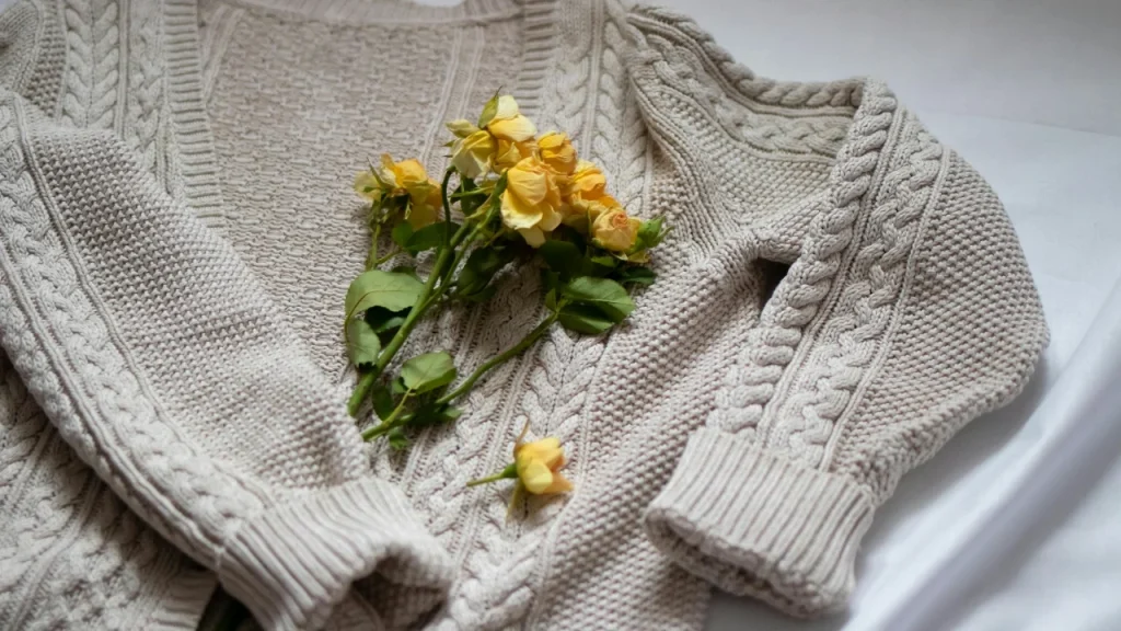 Cream cable knit sweater with detailed stitch texture and floral styling
