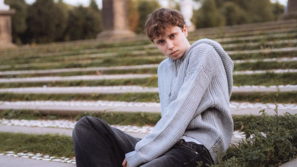 Grey half zip sweater with hooded knit texture worn in an outdoor garden setting
