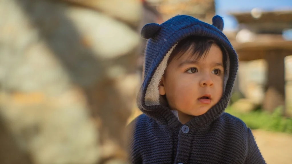 Child wearing a navy knit hoodie with button front and soft lined hood