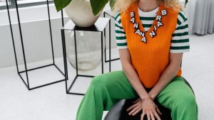 Woman wearing an orange V-neck sleeveless sweater over a striped T-shirt