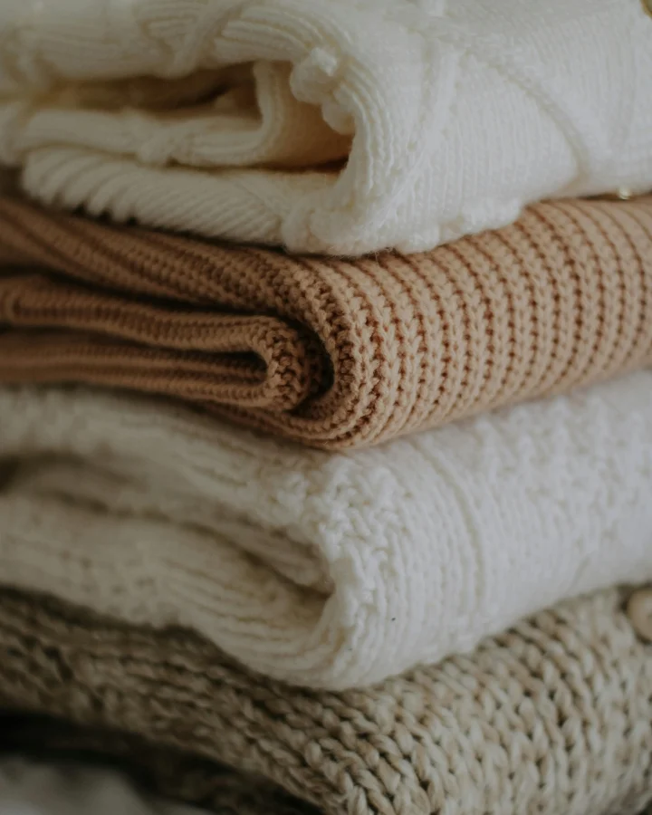 Folded wool zip up sweater and cashmere knitwear showing soft handfeel and texture differences
