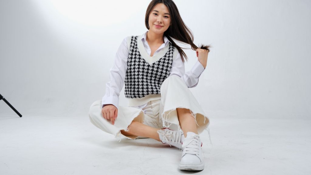Woman wearing a black-and-white houndstooth V-neck sleeveless sweater over a white shirt