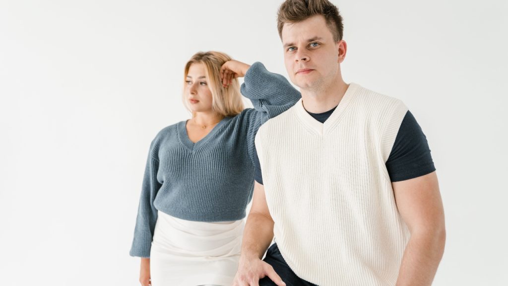 Blue V-neck sleeveless sweater layered over a white ribbed turtleneck