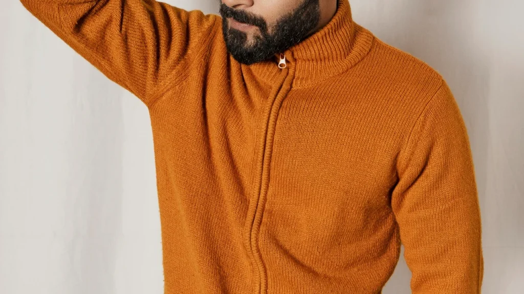 Man wearing an orange full zip wool sweater with ribbed collar and front zipper