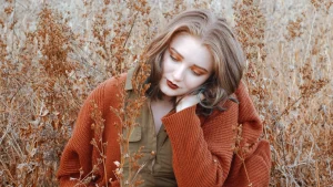 Cardigan Sweater in rust color worn outdoors in a dry autumn field.