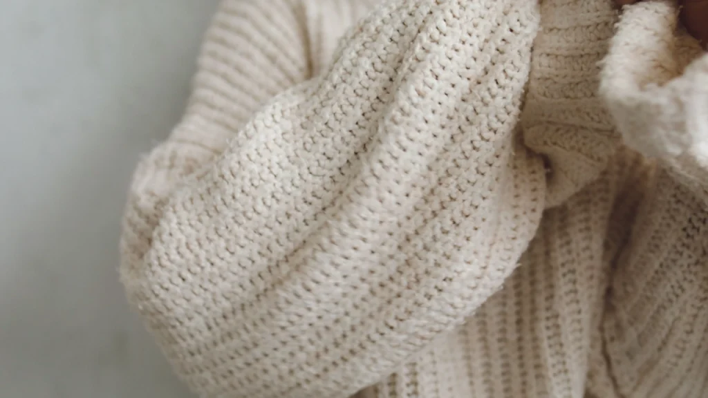 Close-up of cream knit sweater texture for custom clothing manufacturers for knitwear