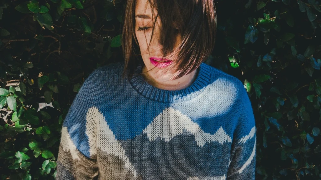 Woman wearing a blue and grey patterned sweater in an outdoor lifestyle setting