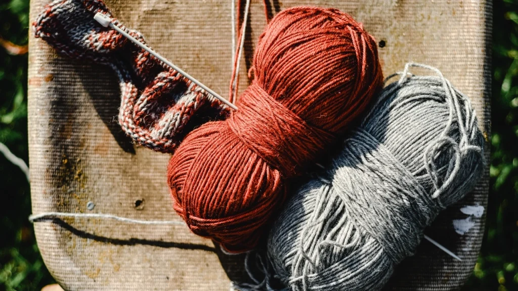 Custom knitwear yarn balls and knitting sample arranged for sweater design and material selection.
