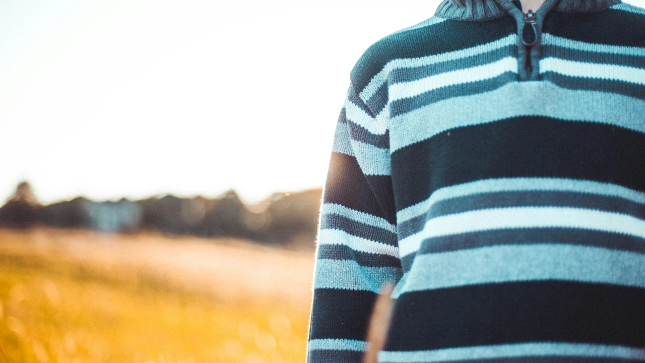 Striped half zip sweater with ribbed collar and front zipper detail in an outdoor setting