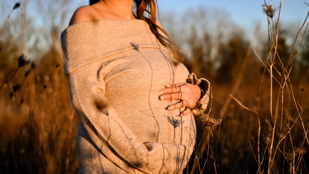 Woman wearing an off-shoulder knit dress in a golden outdoor field.
