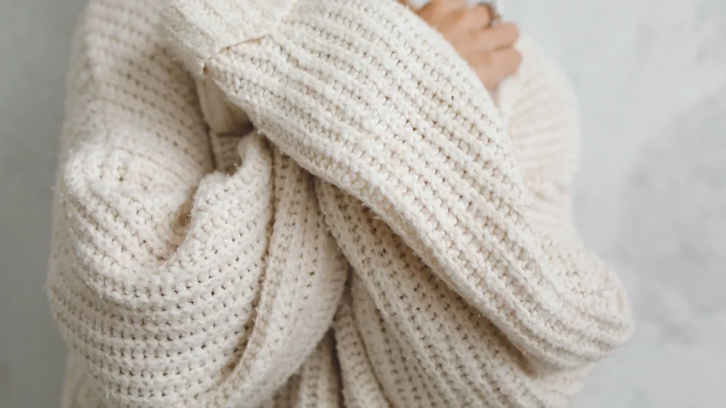 Close-up of a cream knit jumper showing chunky yarn texture and oversized sleeves