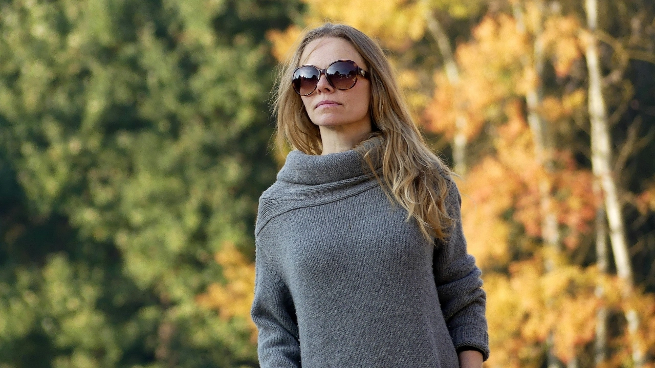 Woman wearing a grey knit maxi dress with a soft cowl neckline in an autumn outdoor setting