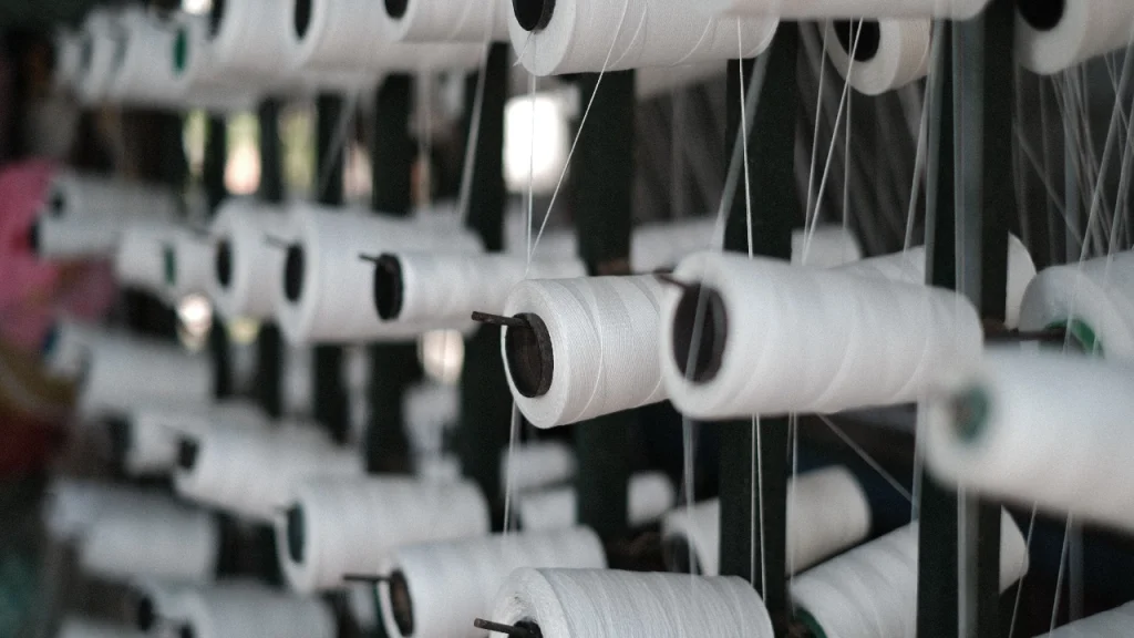 White yarn spools arranged in a knitwear factory before sweater knitting production