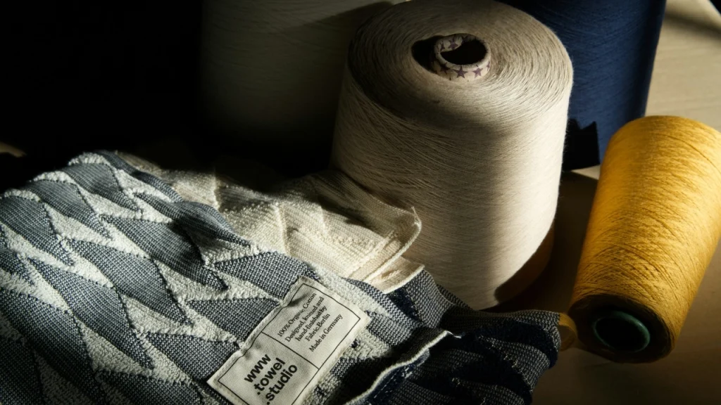 Yarn cones and knitted fabric swatch prepared for knitwear factory development