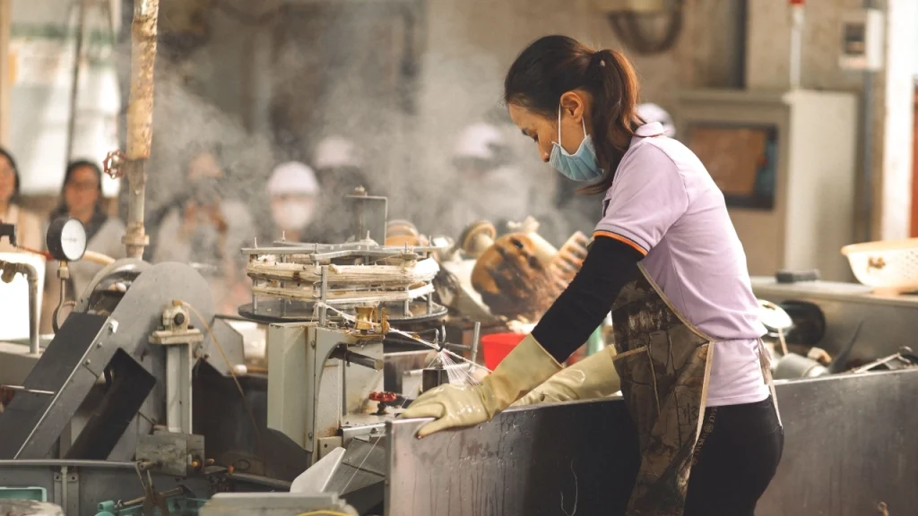 Worker handling yarn processing equipment in a knitwear factory finishing area