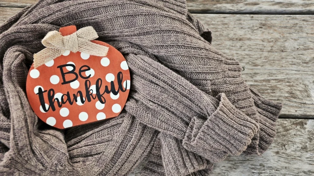 Knitwear Manufacturer folded ribbed sweater displayed with a seasonal thank-you sign.