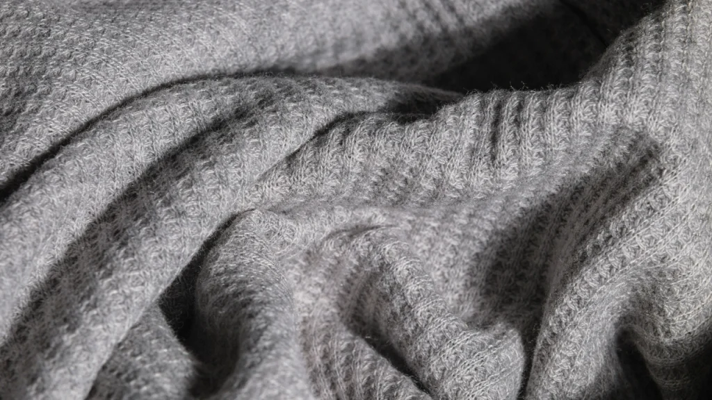 Close-up of grey knitted fabric showing stitch density and surface texture