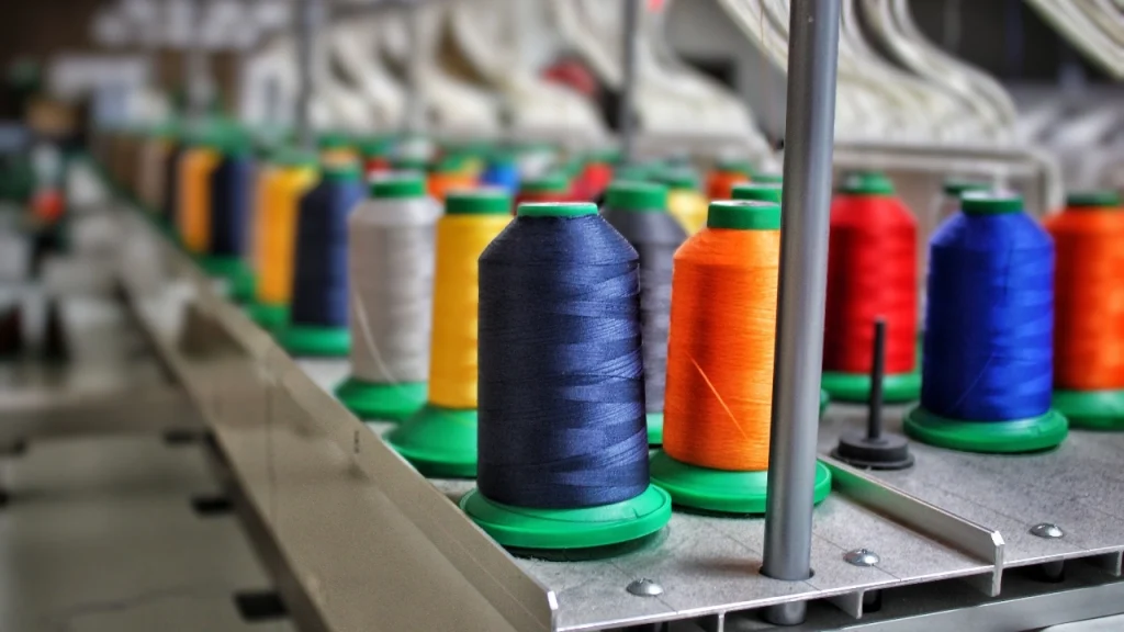 Knitwear Manufacturer industrial thread cones arranged on production equipment for apparel manufacturing.