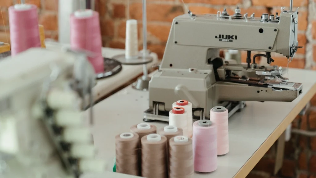 Knitwear Manufacturer sewing machine with thread spools for knitwear assembly and finishing.