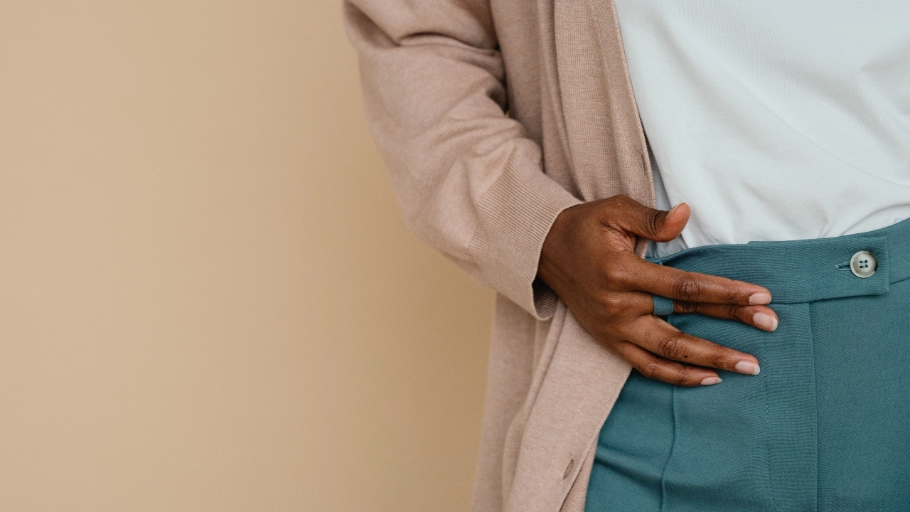 Close-up of a beige mens cardigan paired with a white shirt and blue trousers.
