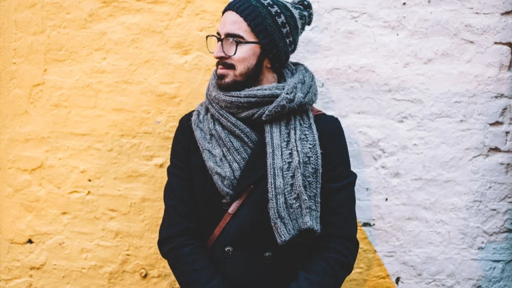 Man wearing a gray knitted scarf and beanie, showing winter Mens Knitwear accessories and cold-weather styling.