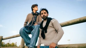 Two men wearing neutral knit sweaters outdoors, showing casual Mens Knitwear layering and seasonal styling.