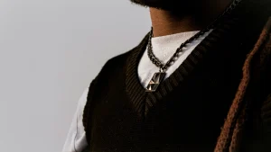 Close-up of a black mens sleeveless jumper layered over a white T-shirt with chain accessories.