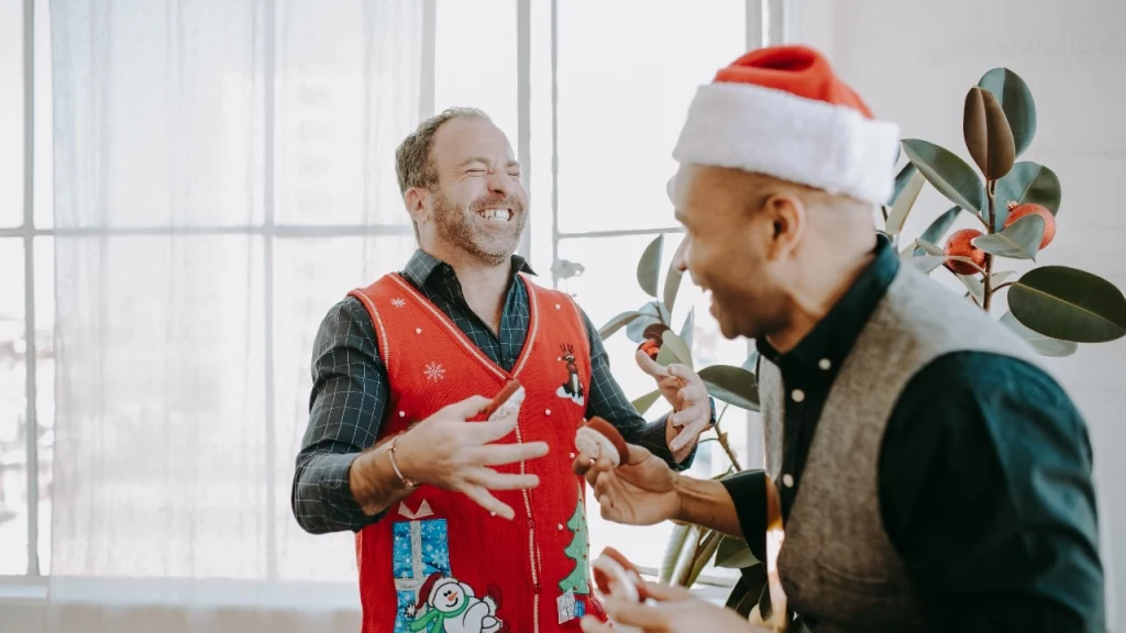 Man wearing a red holiday mens sleeveless jumper at a festive indoor gathering.