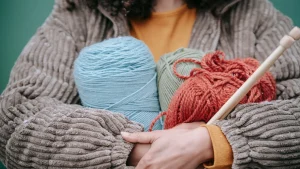 Person holding colorful yarn balls for OEM knitwear material selection and product development
