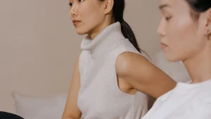 Woman wearing light grey sleeveless knitwear with a ribbed turtleneck and clean armhole finish