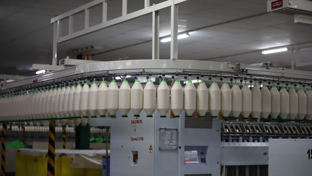 Sweater Factory yarn spinning equipment with multiple yarn cones used in knitwear production.