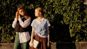 Woman wearing a light blue V-neck sweater vest over a white collared shirt outdoors