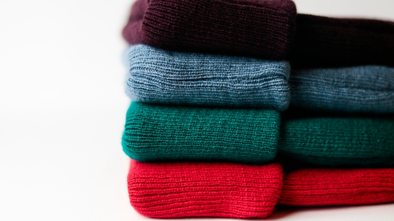 Wholesale knitted sweaters production tools with scissors, crochet hooks, yarn, and textured knit fabric.