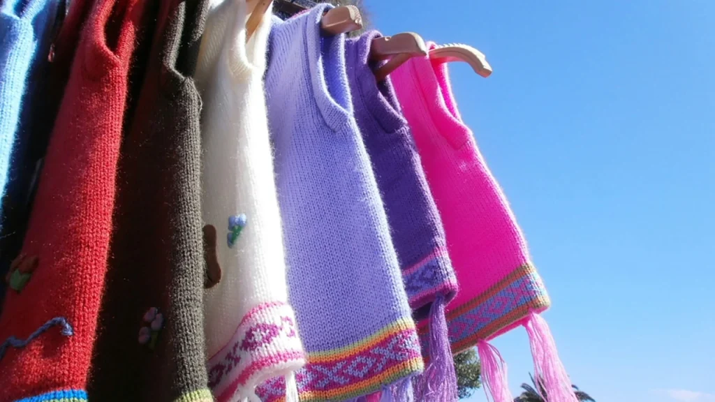 Wholesale knitted sweaters folded in layered neutral and warm colors for collection display.
