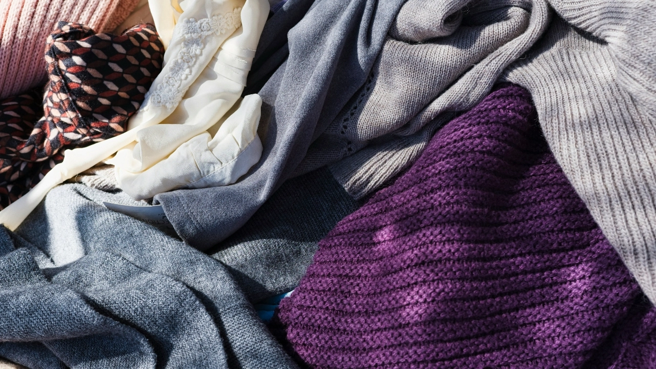 Wholesale knitwear assortment with folded sweaters and mixed fabric textures in neutral and colorful tones.