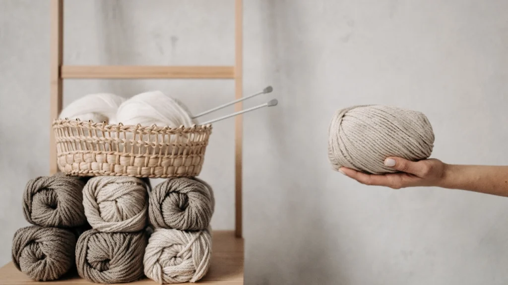 Wholesale knitwear yarn balls and knitting needles showing material selection for sweater production.