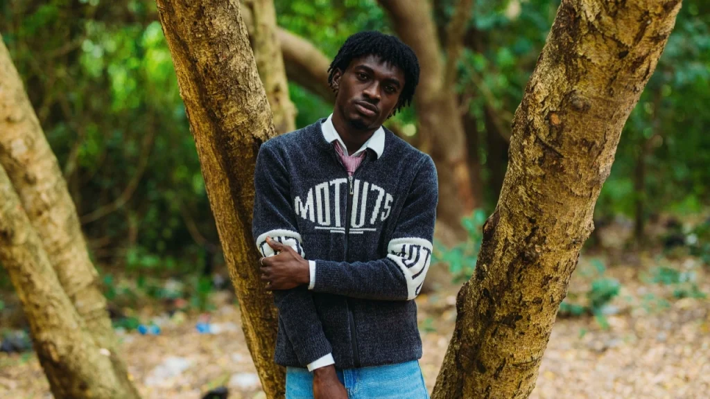 Zip cardigan worn by a man outdoors, featuring navy knit texture and graphic sleeve details.
