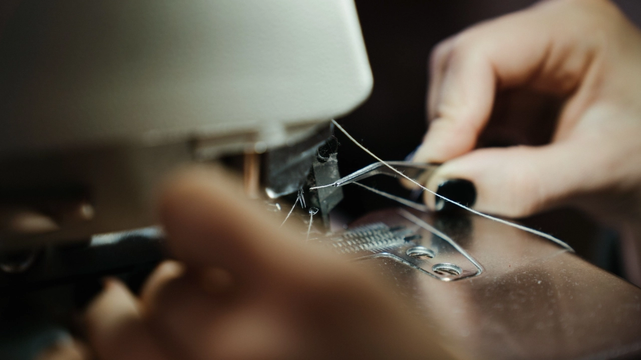 Close-up of a worker threading a sewing machine inside a sweater factory.