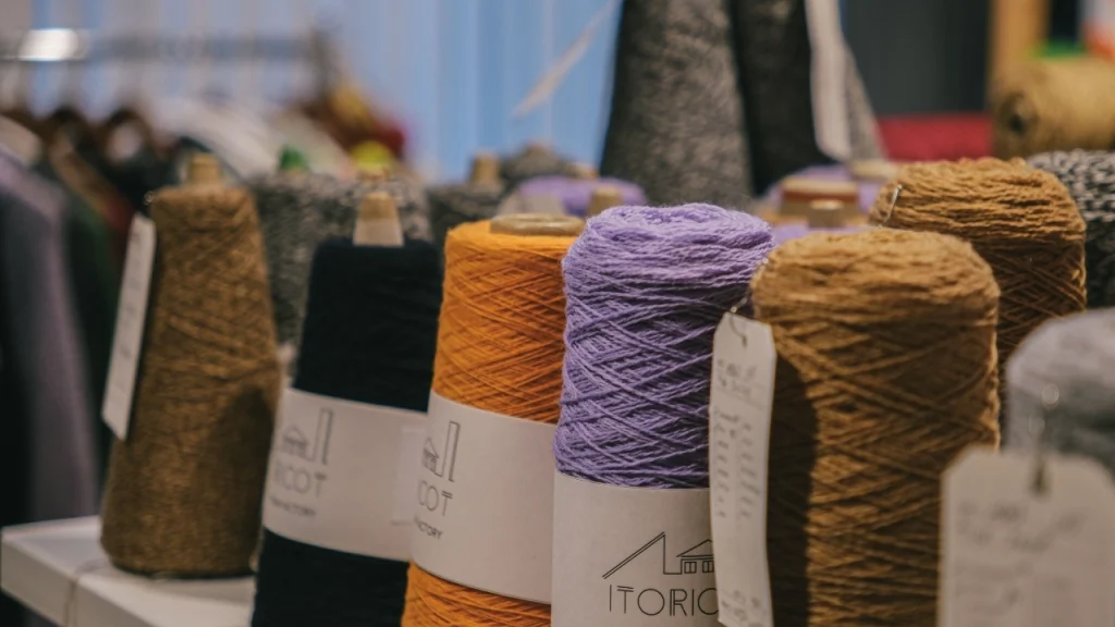Colorful yarn cones arranged for knitwear production inside a sweater factory.