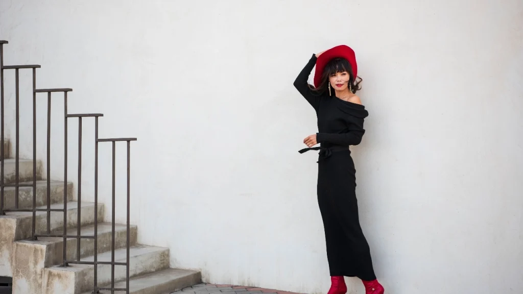 Woman wearing a black off-shoulder knit dress with bold fashion styling.