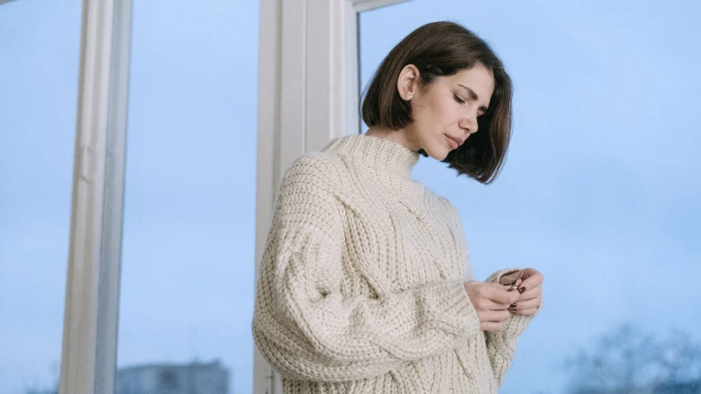 Woman wearing a cream cable Cotton Knitwear sweater indoors.