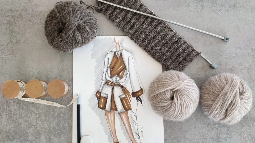 Custom Knitwear design sketch with yarn balls, knitting needles, and a knitted swatch.
