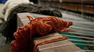 Orange yarn placed on a knitting machine during Knitwear Production.