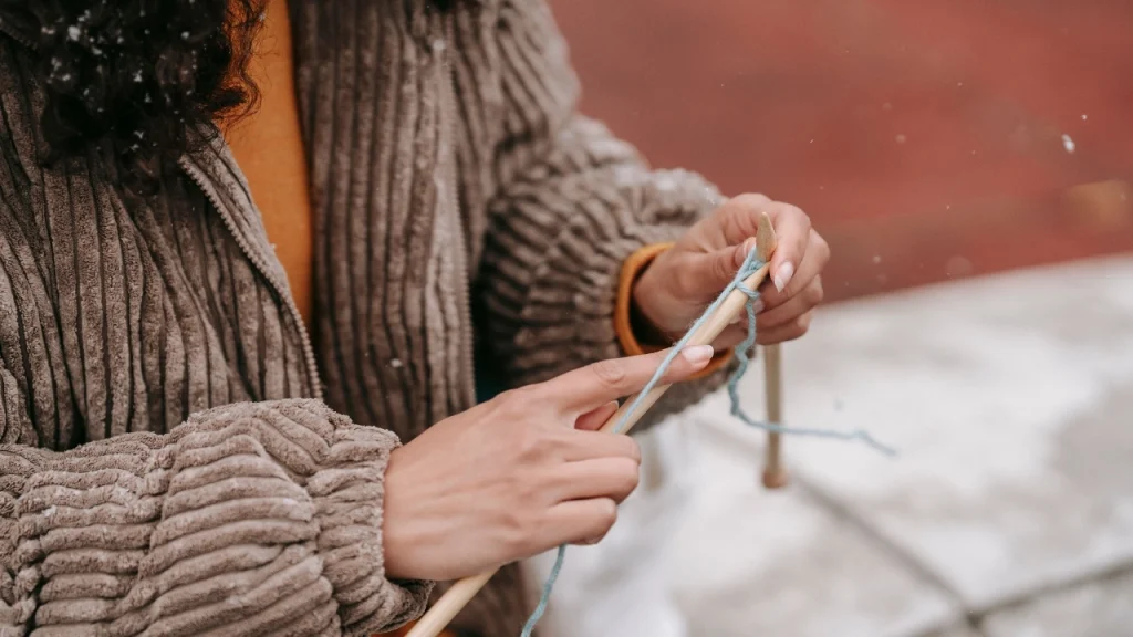 Close-up of hands knitting yarn for knitwear supplier production and sample development.