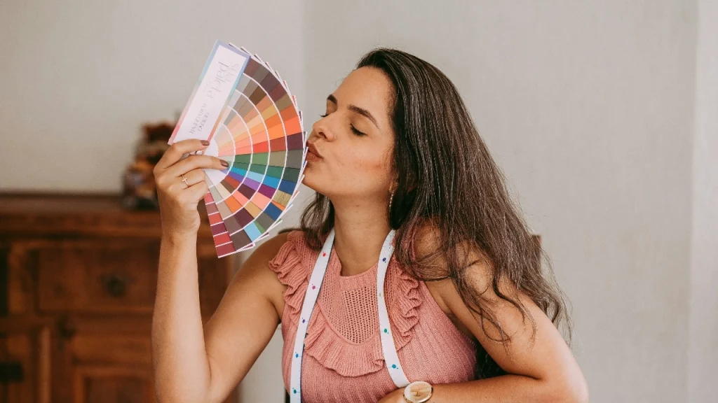 Designer reviewing color cards while wearing a knit top for sweater measurement chart planning.