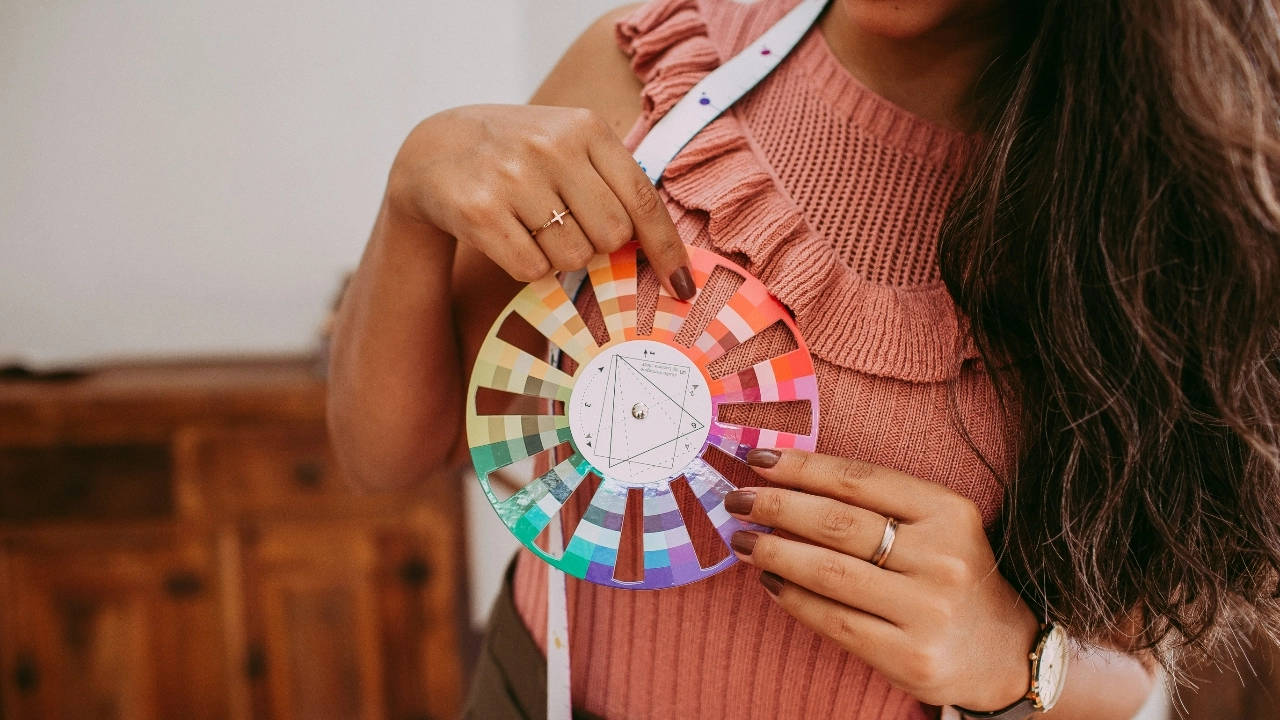 Close-up of a designer selecting colors from a color wheel for sweater measurement chart development.